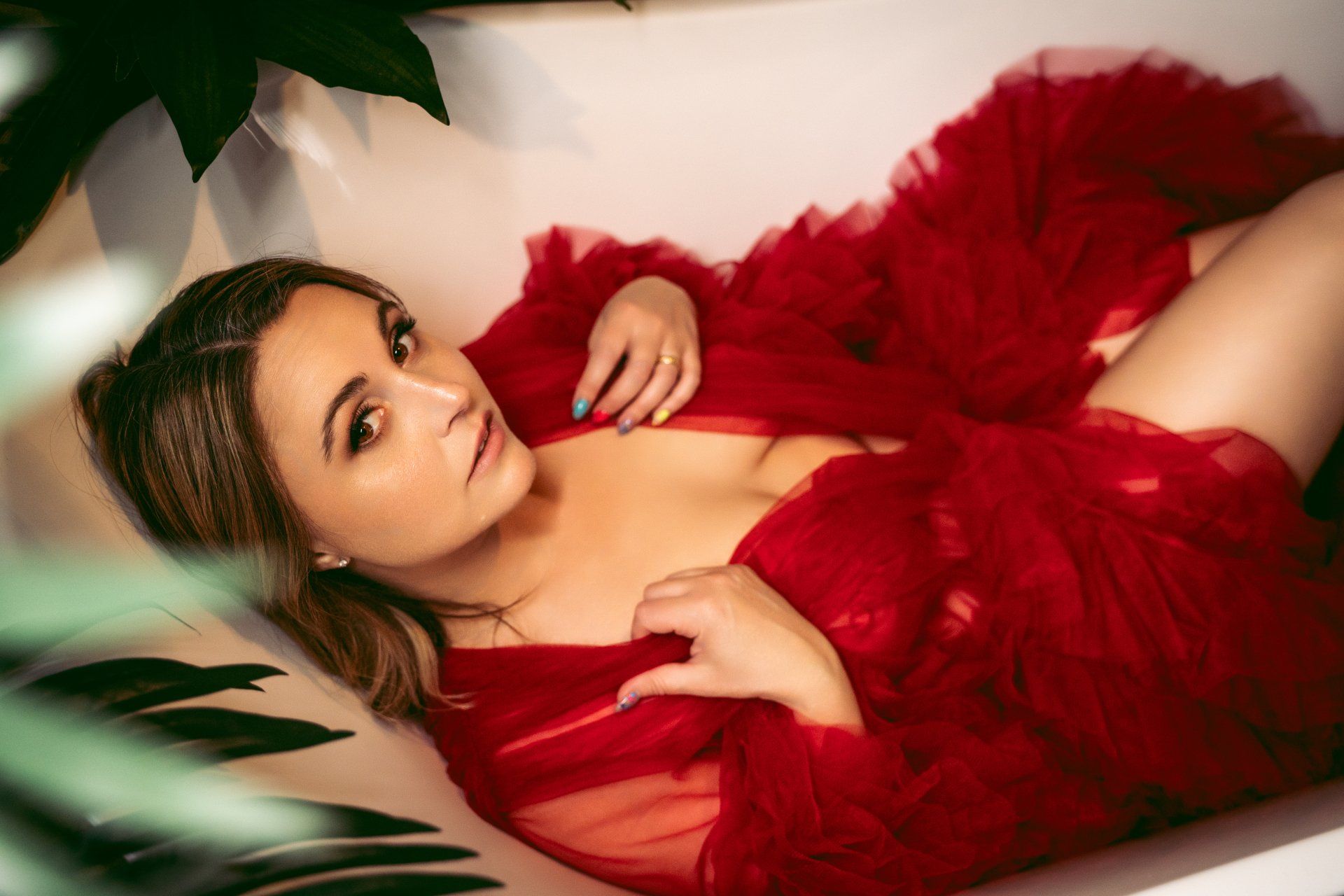 woman laying in bathtub in red robe