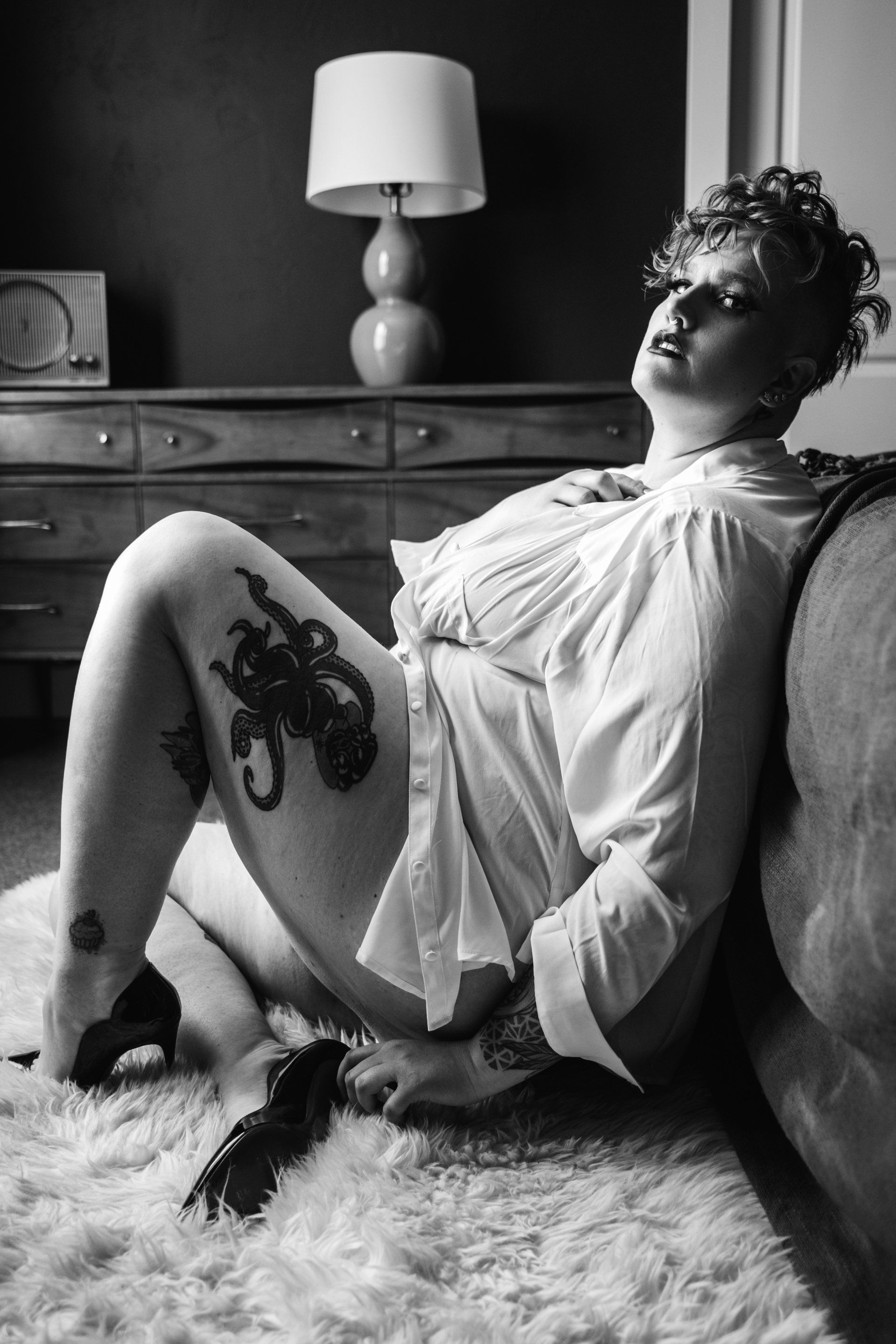 woman in white shirt and high heels sitting next to bed