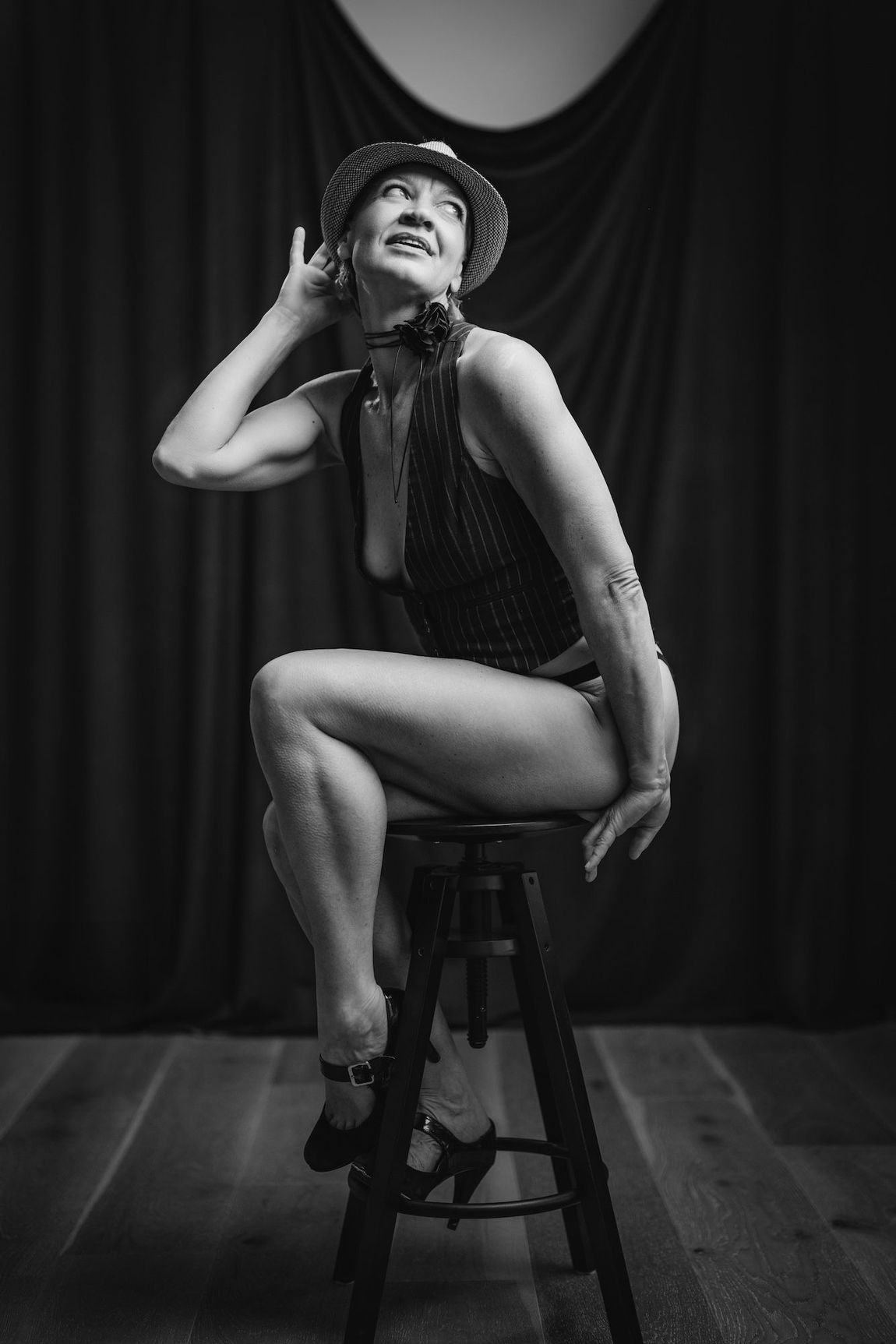 A woman in a bikini sits gracefully on a stool.