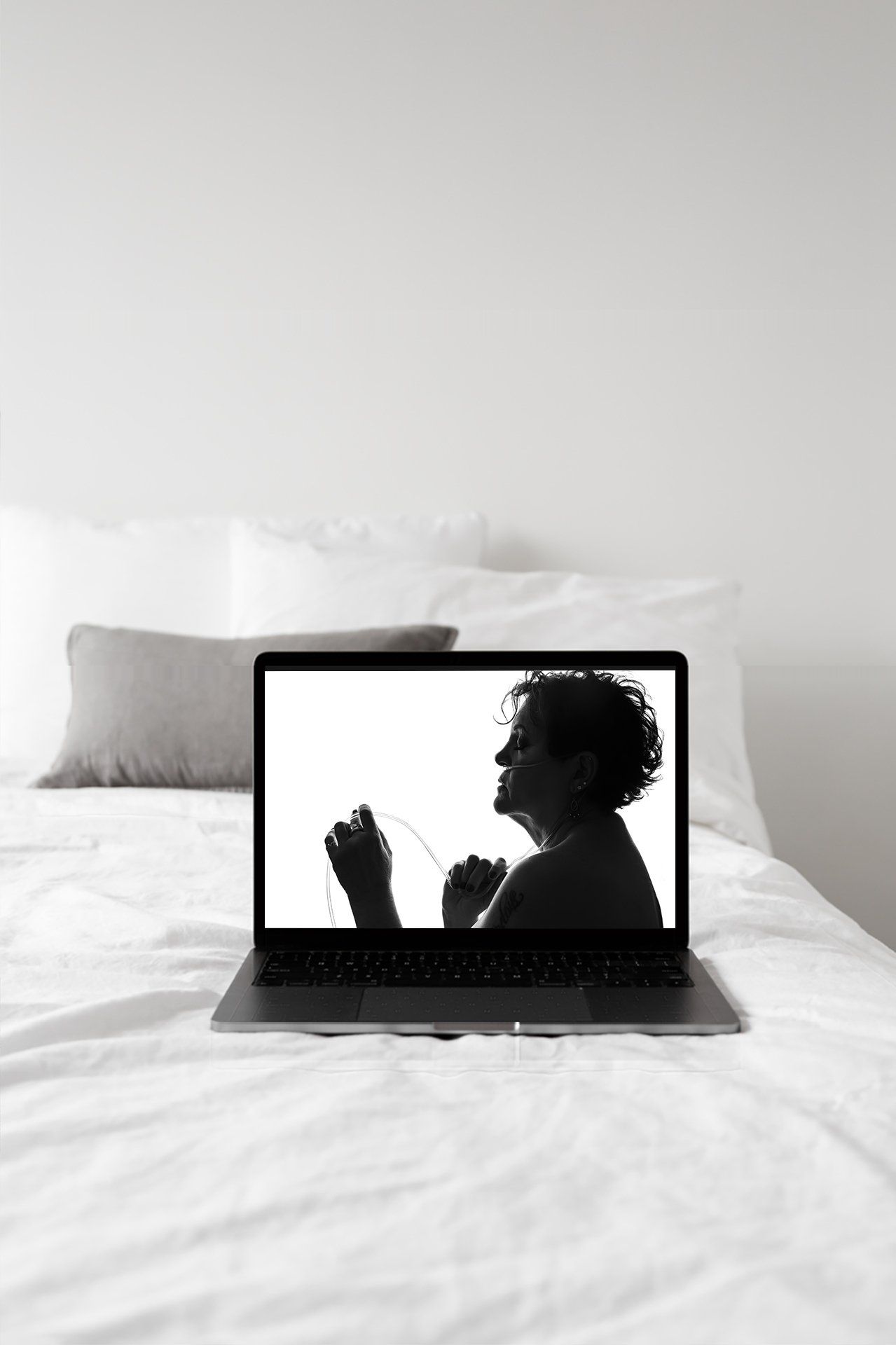 A laptop on a bed with a white sheet.