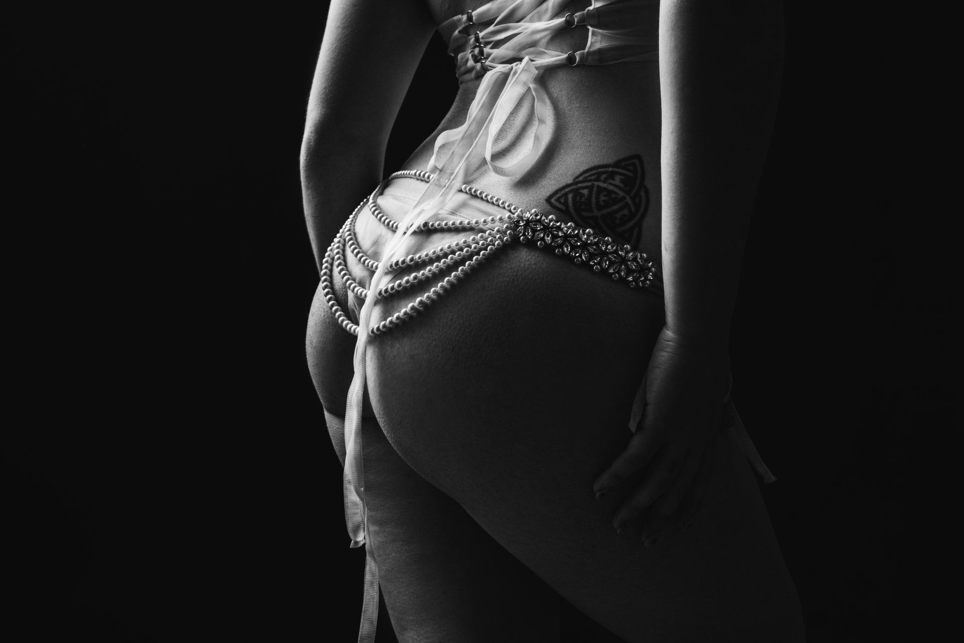 A woman wearing pearls over her buttocks.