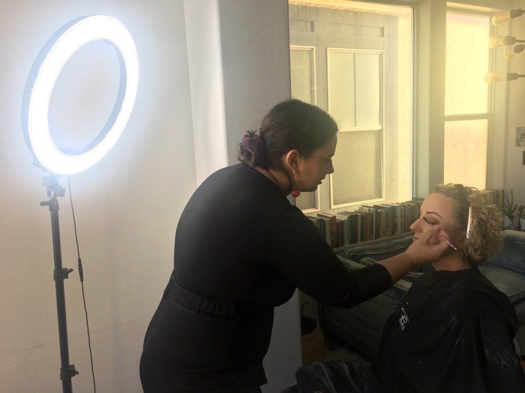 A woman sitting in a salon chair, getting  ready for photoshoot