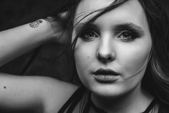 Black and white photo of a tattooed woman posing for the camera.