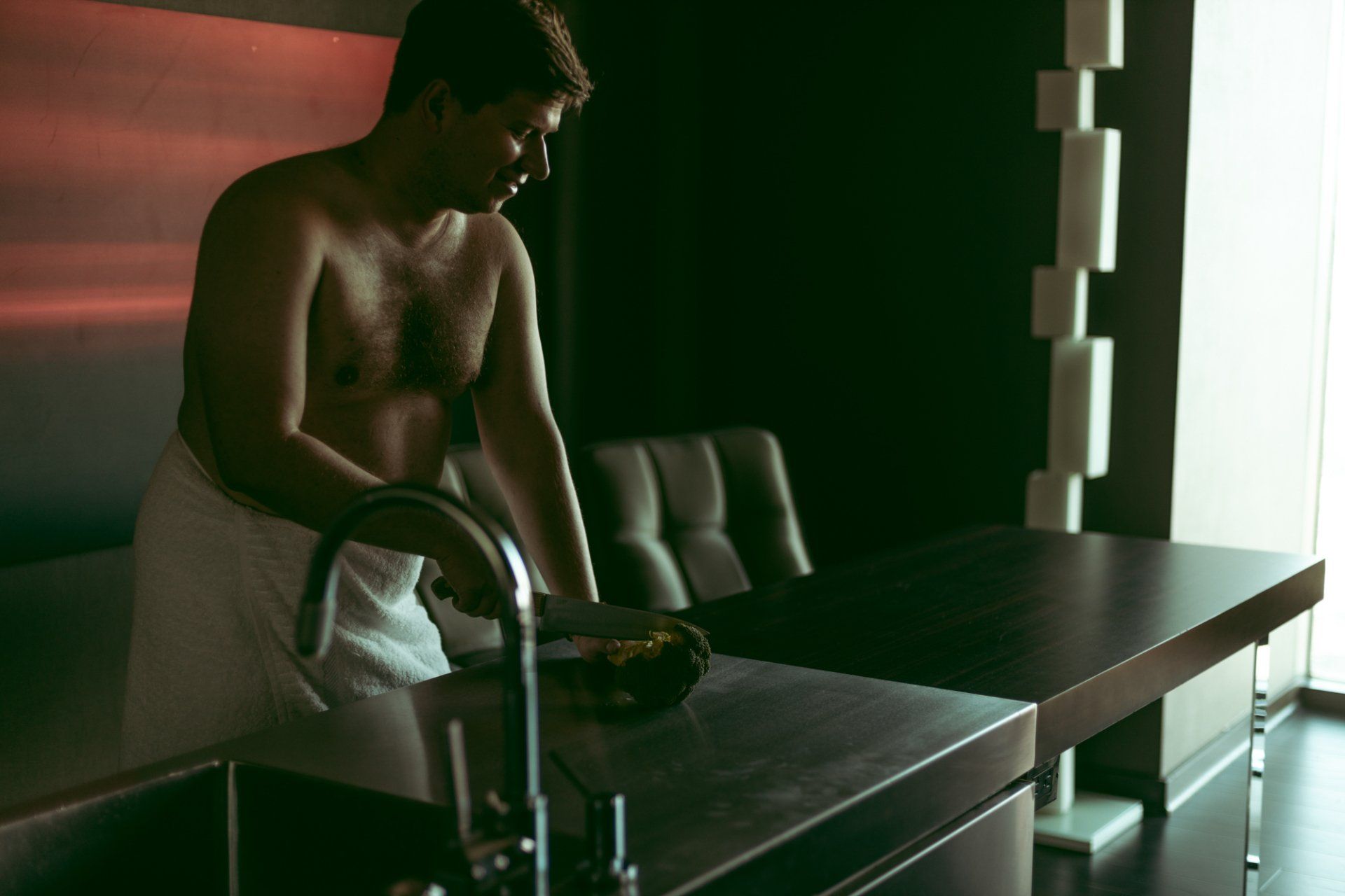 man cutting broccoli wrapped in a towel during boudoir session