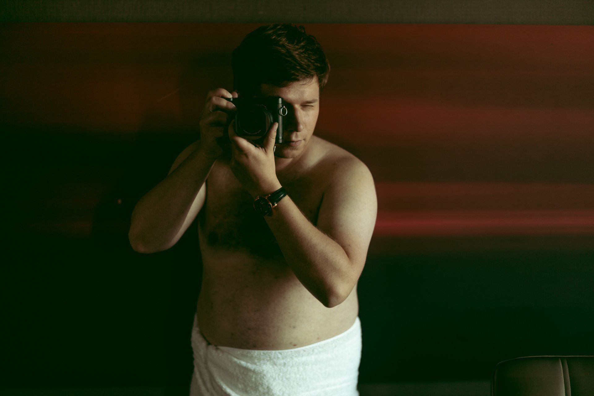 man taking a photograph wrapped in a towel during his boudoir photoshoot