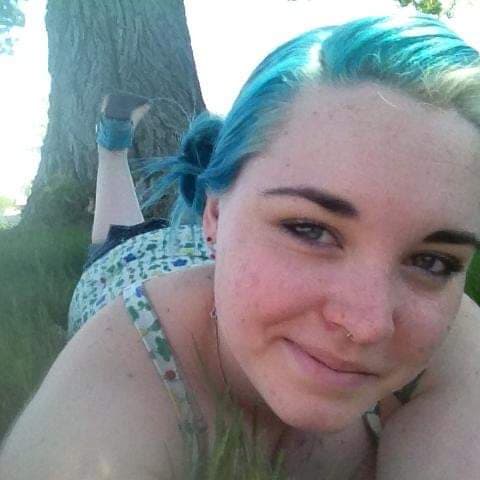 A woman with vibrant green hair enjoying nature on the grass.