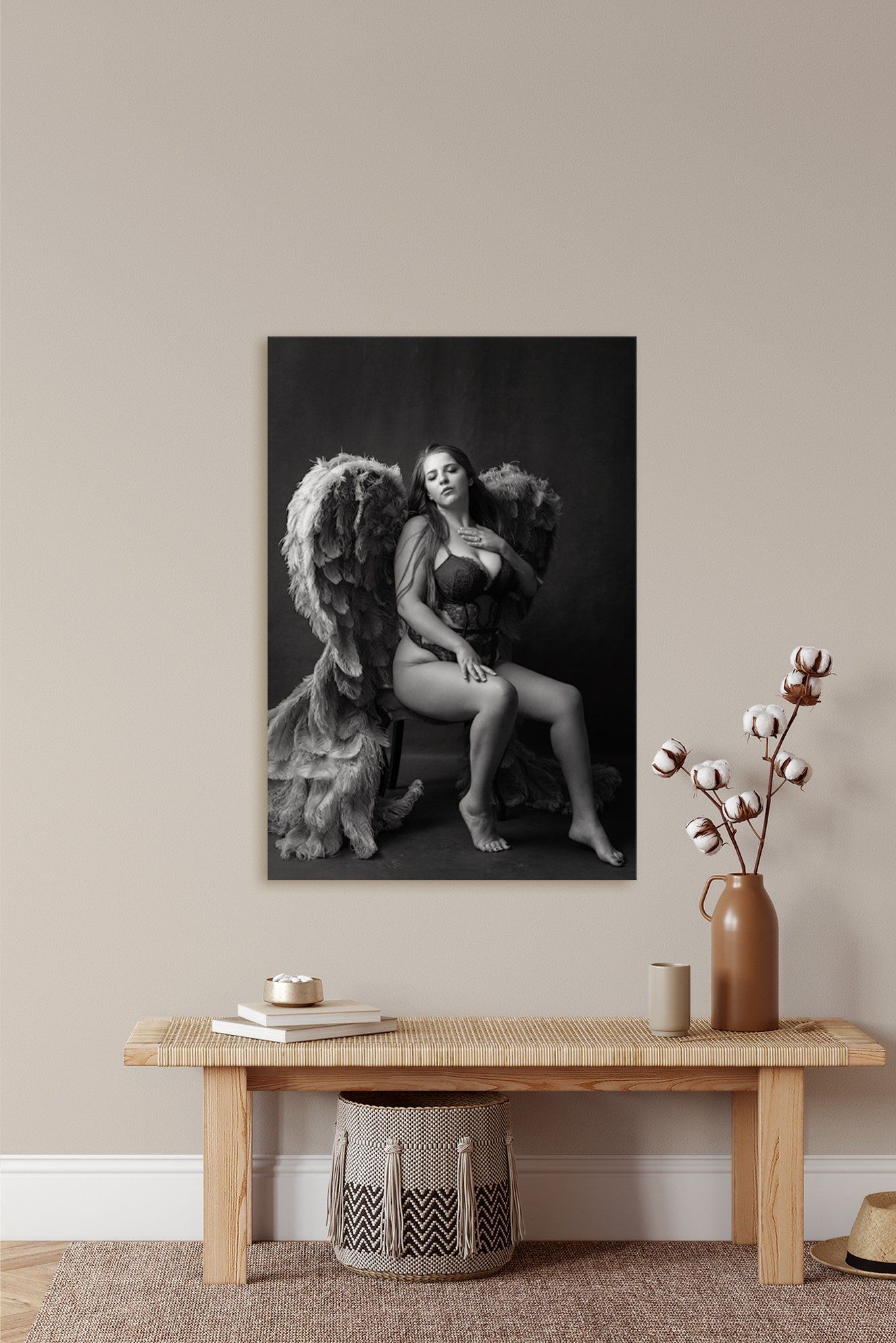 Black & white photo print of angel on rock displayed on wall.