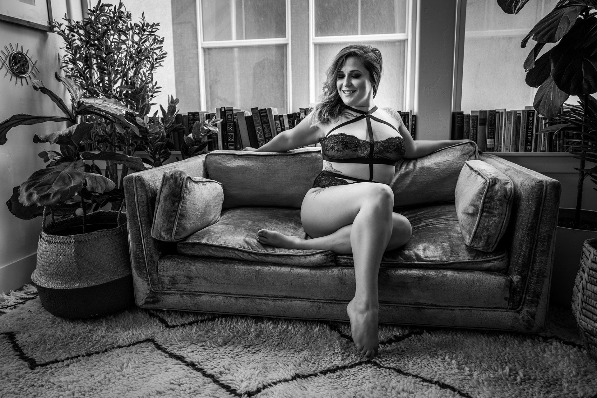 utah boudoir photography woman sitting on a couch in a lingerie looking away and smiling during a boudoir session