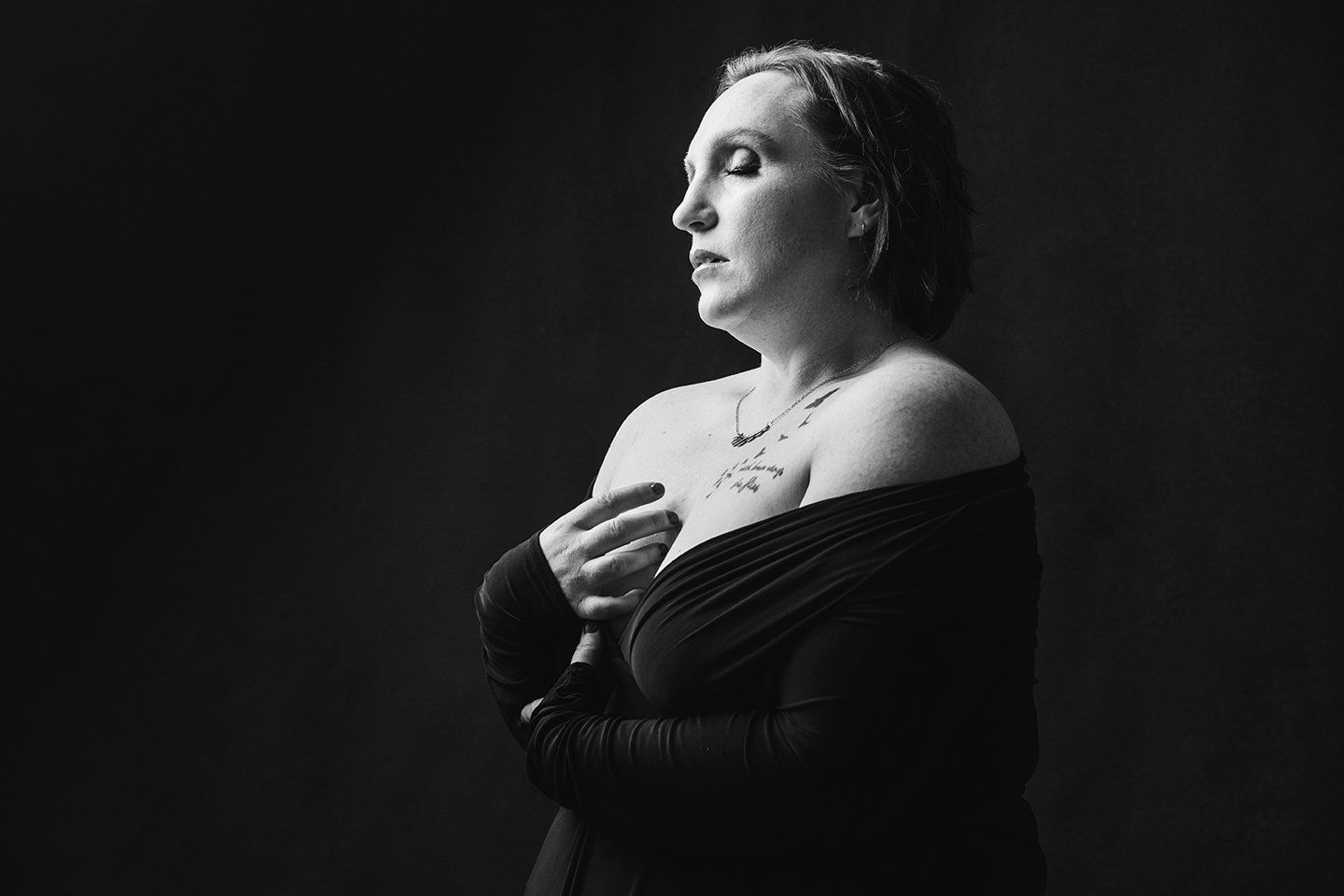 Utah intimate photography woman in a black dress with eyes closed during her boudoir session in Ogden Utah