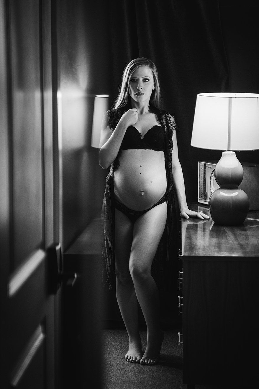 Maternity photo of woman standing next to dresser