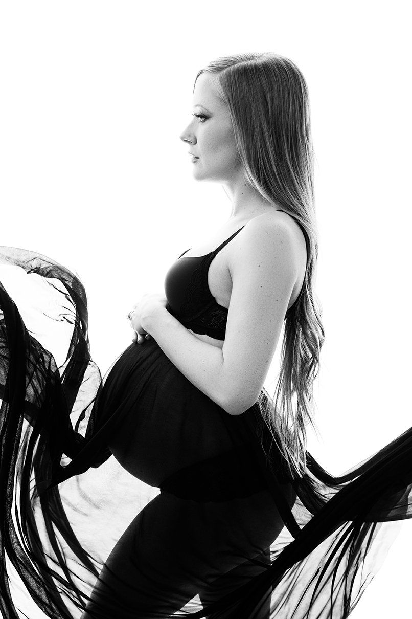 Maternity boudoir image of woman in black flowing skirt