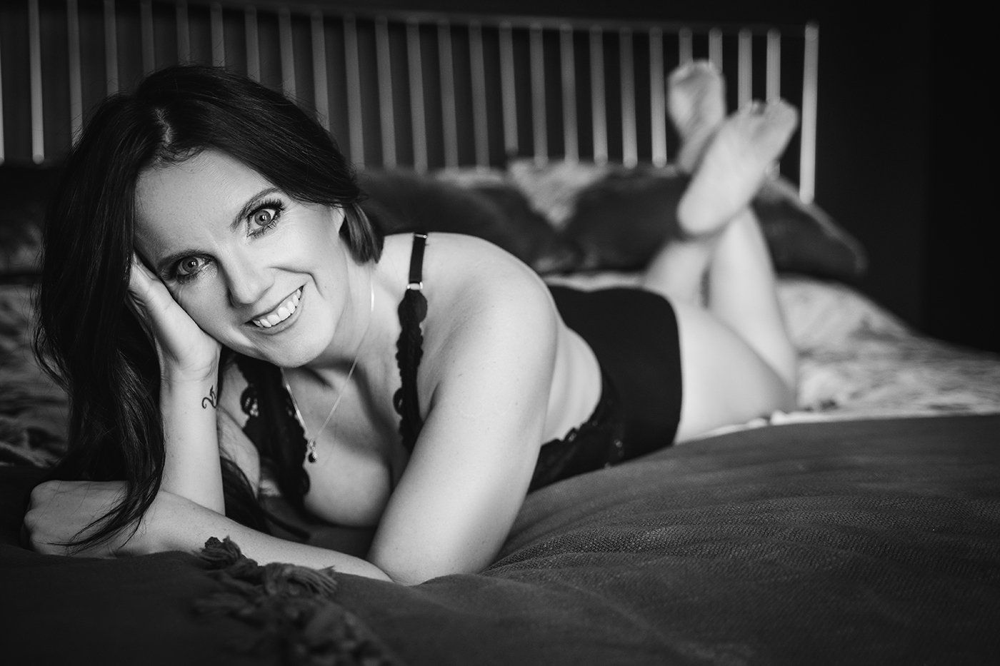 boudoir portrait, woman lying on bed smiling