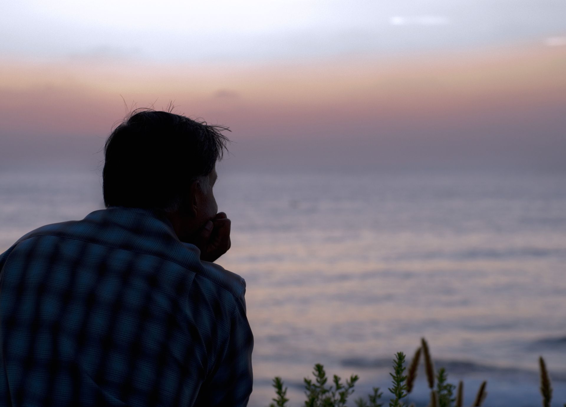 a man in a plaid shirt looks out over the ocean