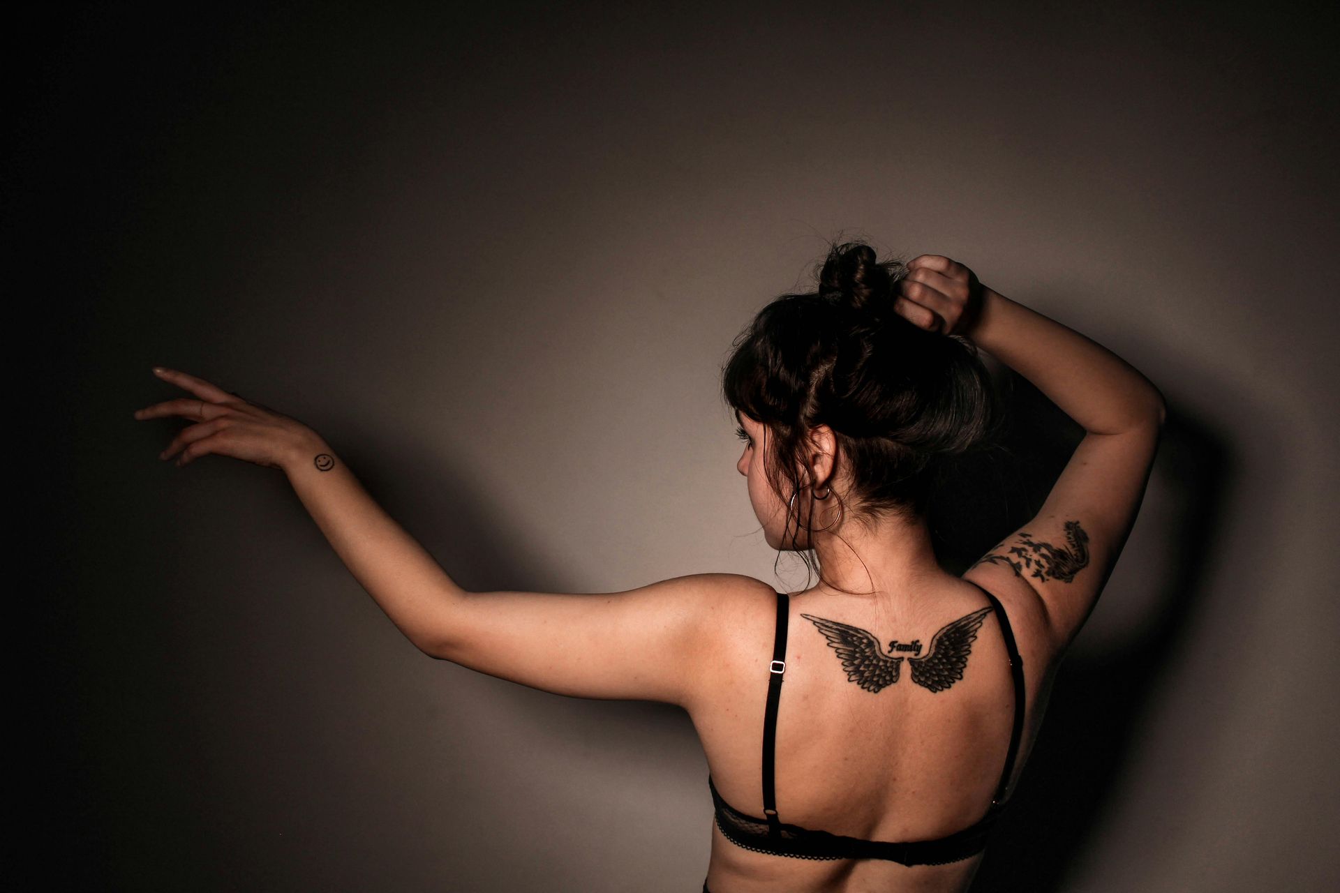 A woman in a black bra has a tattoo on her back.