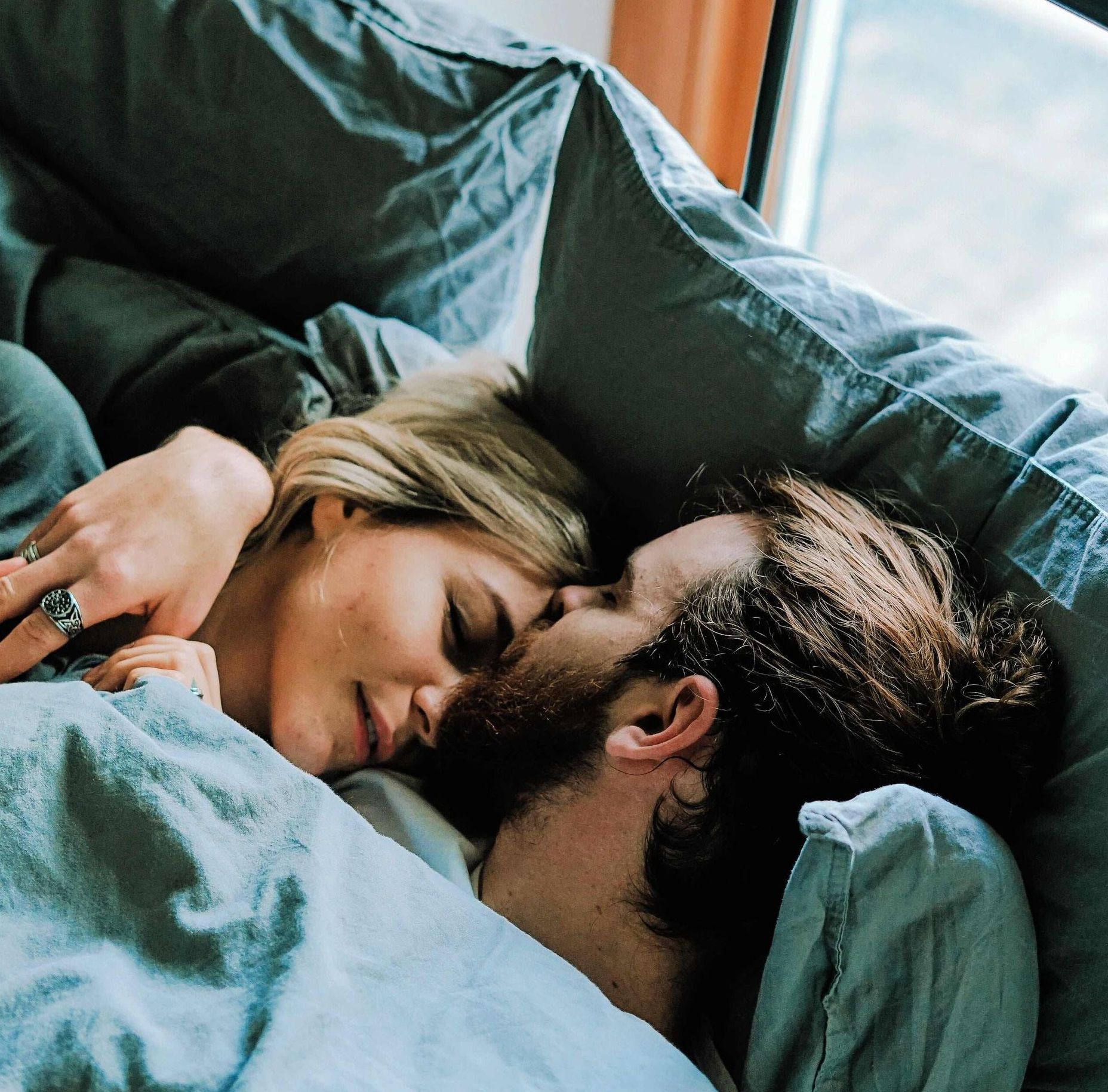 A man and a woman are laying in bed with a yellow banner that says for couples