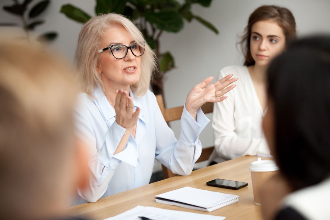 A Woman Is Sitting at A Table Talking to A Group of People — Moving Beyond OK In Beenleigh, QLD