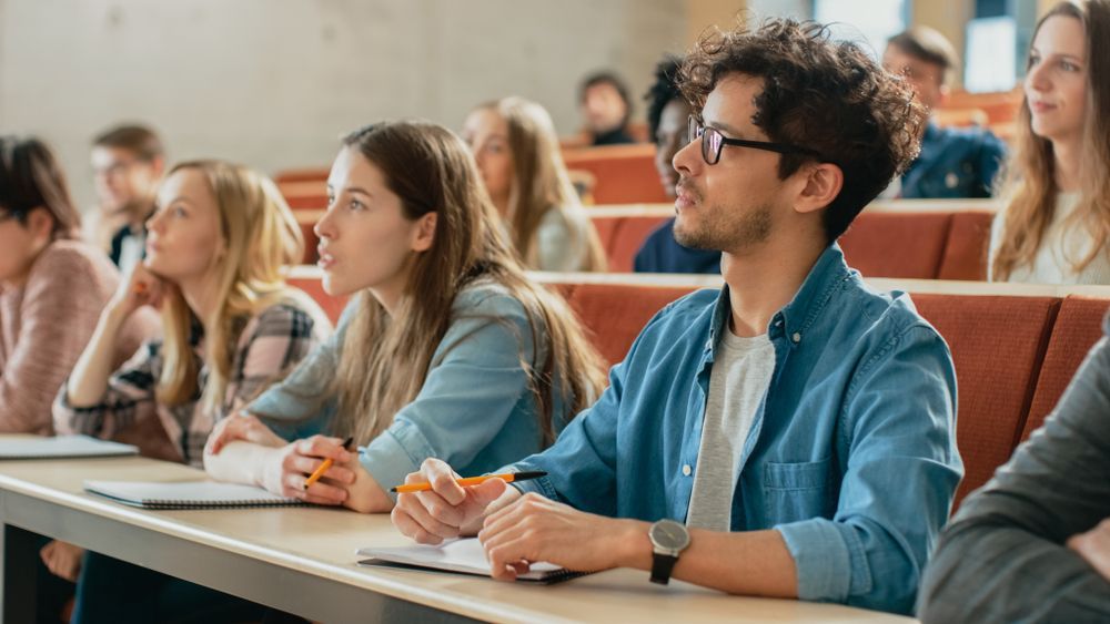 A Group of Students Are Sitting at Desks in A Lecture Hall — Moving Beyond OK In Mount Warren Park, QLD
