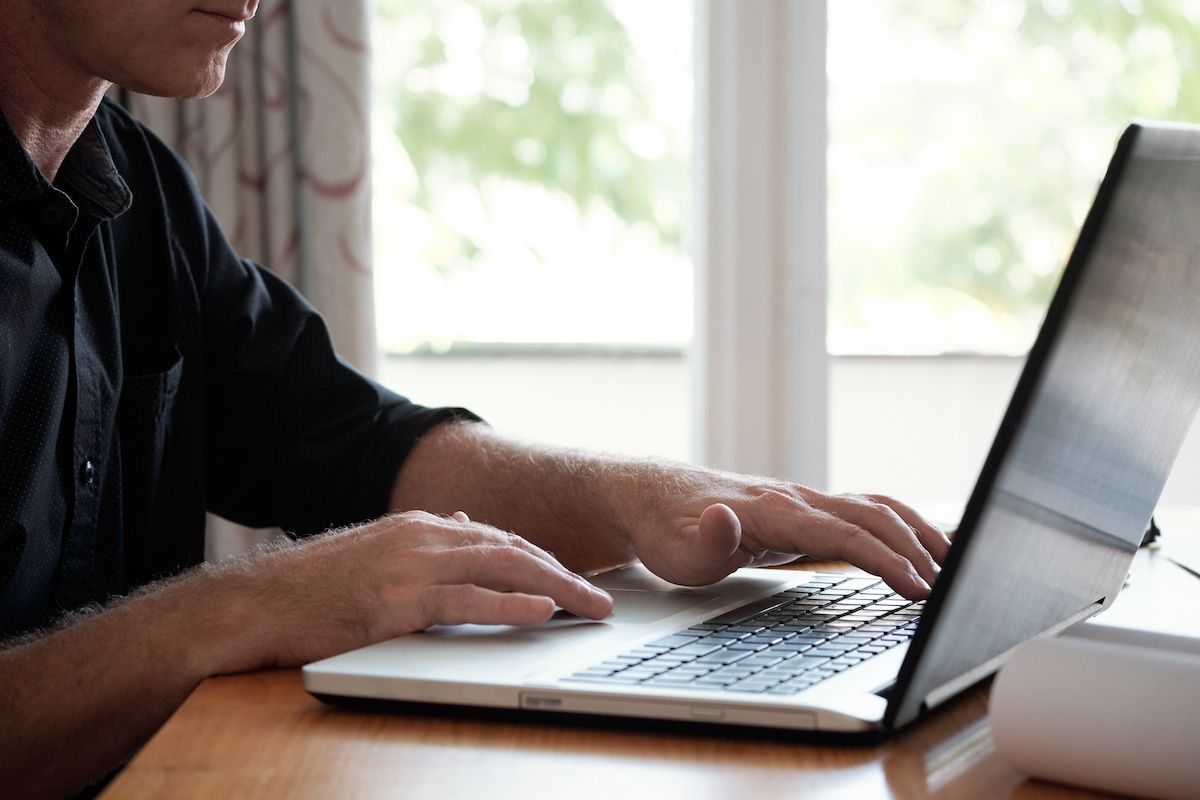 A Man Browses a Laptop at His Kitchen Table, Looking at Online Auction Through Atterberry.