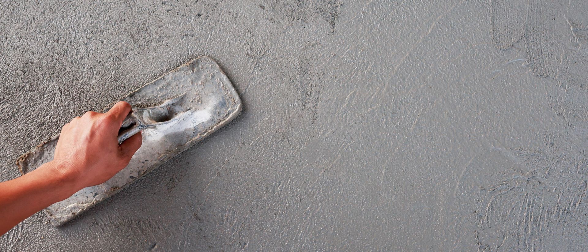 Close-up of hand trowel smoothing fresh concrete patch, worked on by Elite Form Concrete in Rio Rancho, NM.