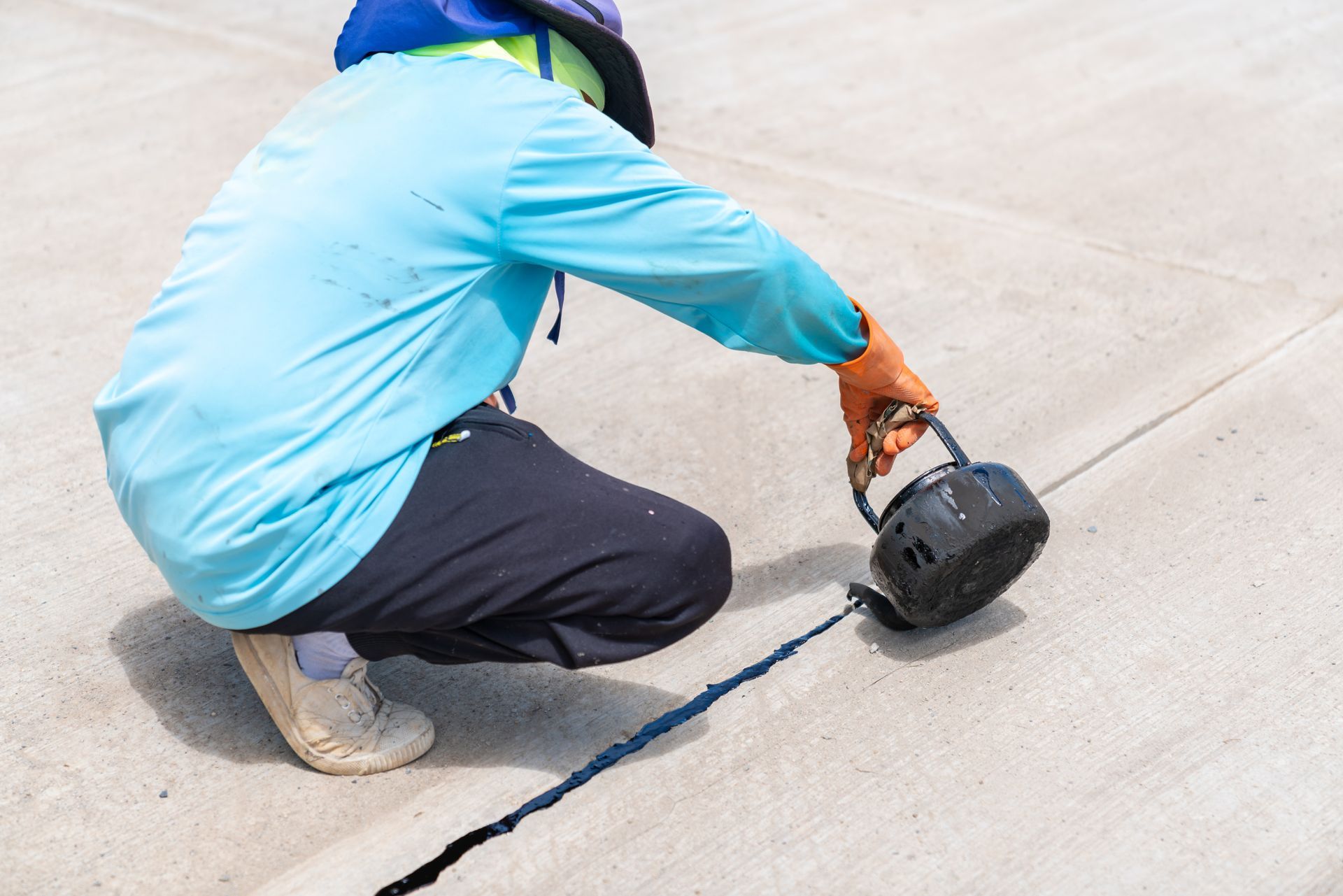 Worker grinding concrete crack with hand tool for sealant, worked on by Elite Form Concrete in Eagle Mountain, UT.