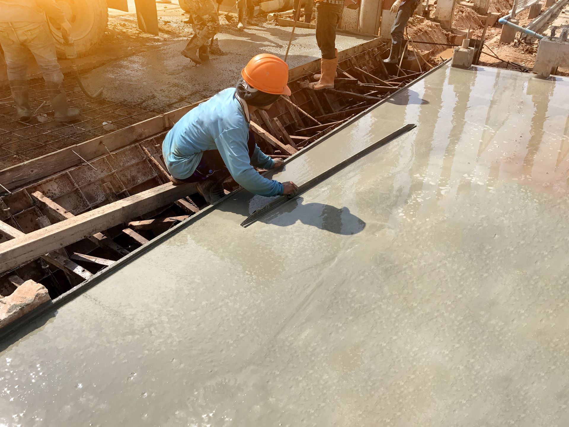 Worker smoothing freshly poured RV pad with trowel, worked on by Elite Form Concrete in Eagle Mountain, UT.