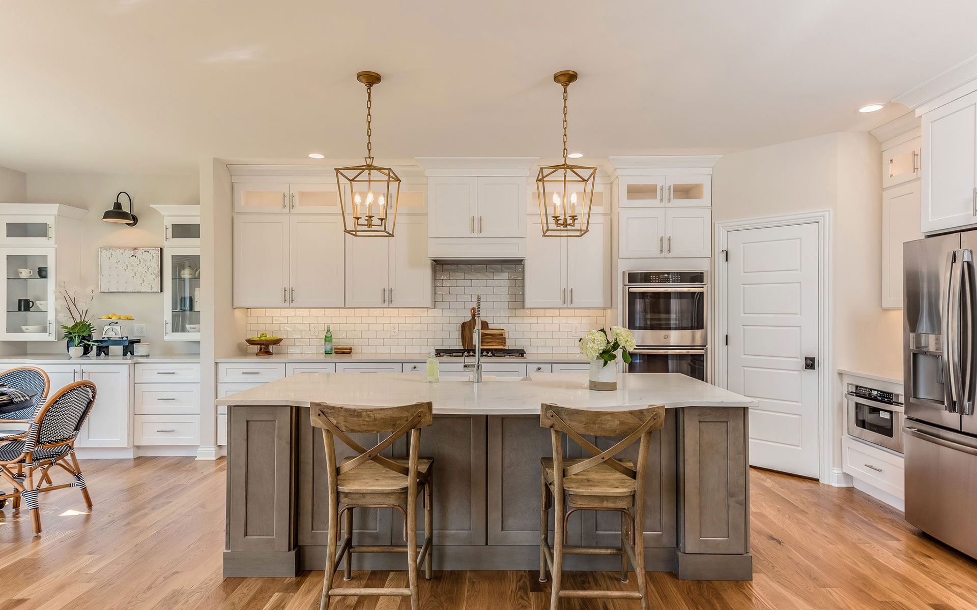 A kitchen with white cabinets , stainless steel appliances , hardwood floors and a large island.