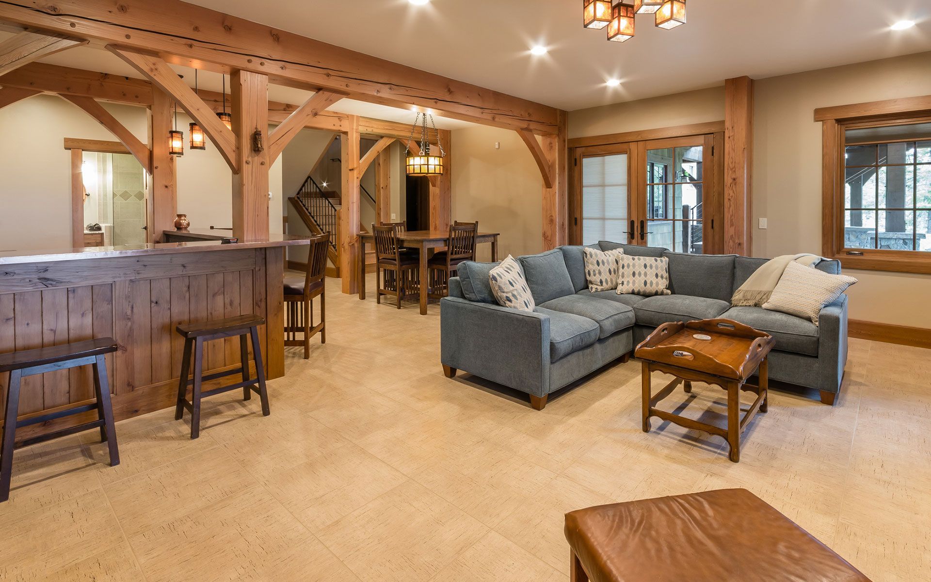 A living room with a blue sectional couch and a wooden bar.