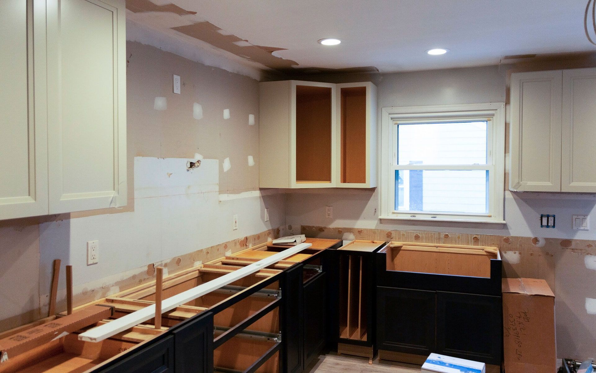A kitchen under construction with wooden cabinets and a window.