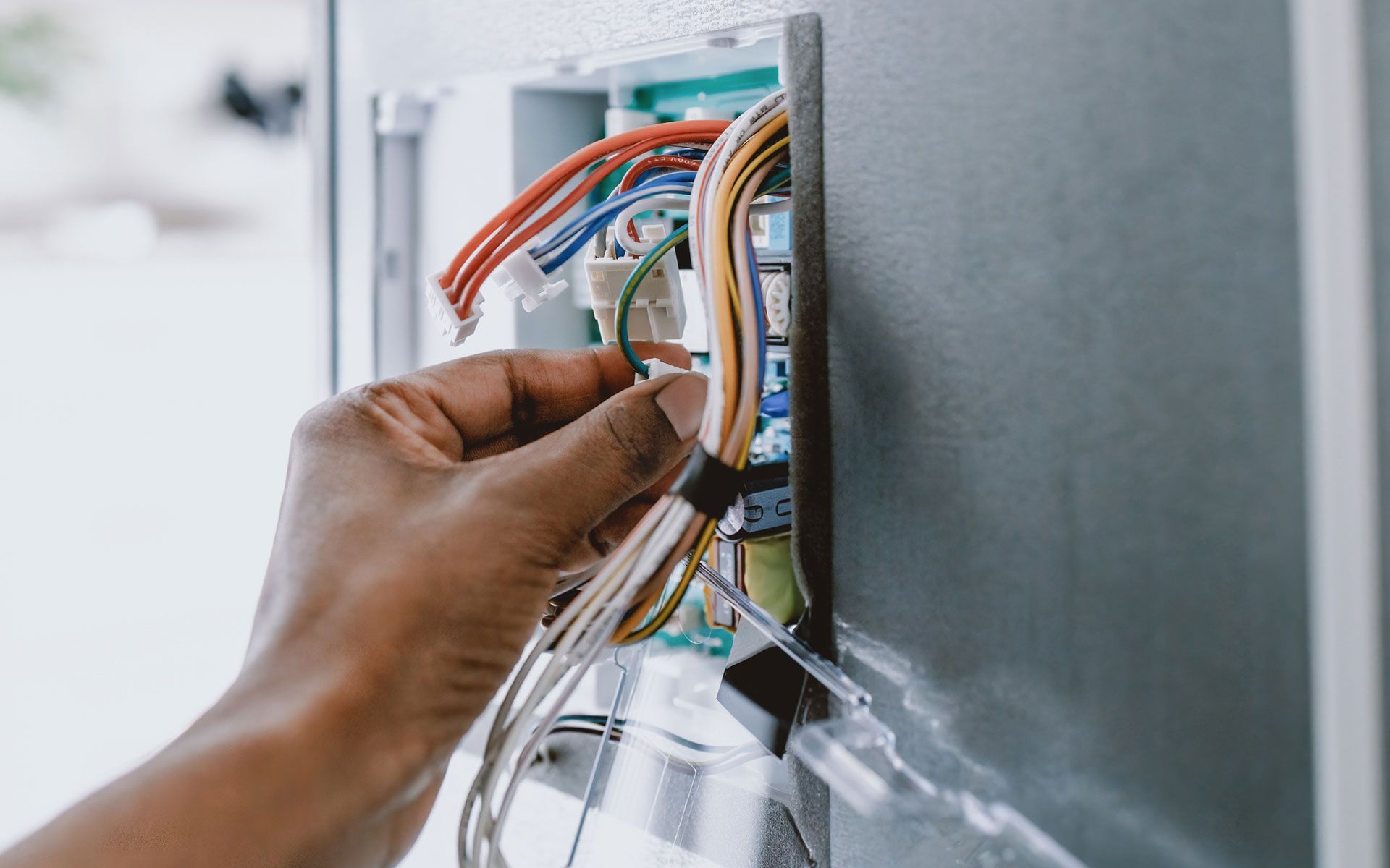 A person is fixing an electrical box with a screwdriver.