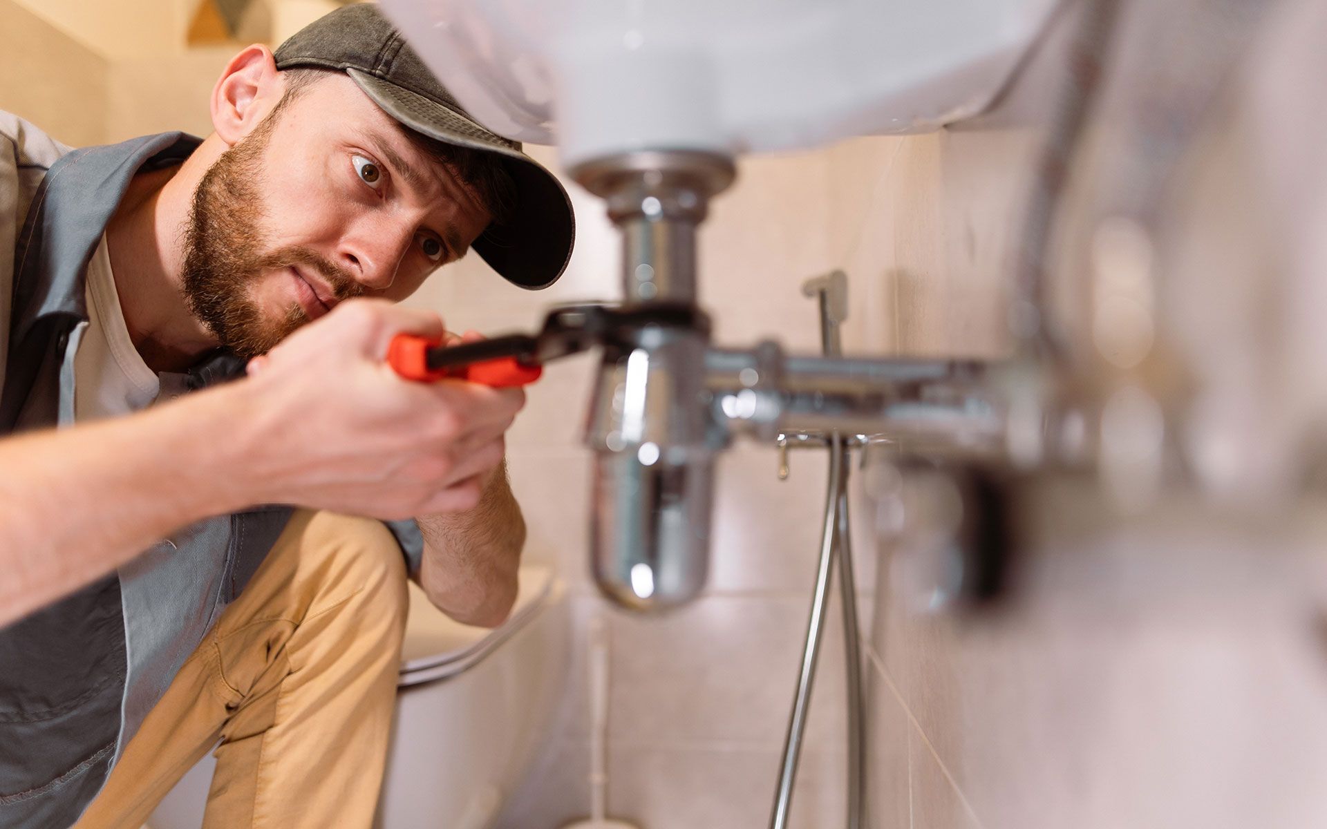 A man is fixing a sink with a wrench.