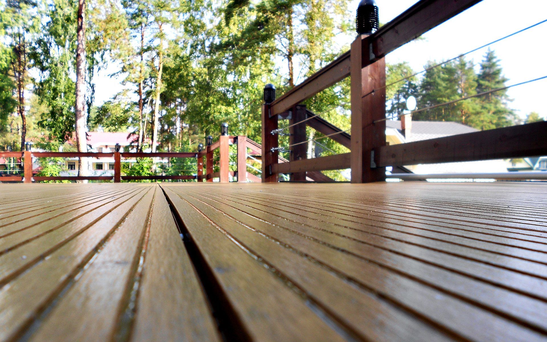 A wooden deck with a fence and trees in the background