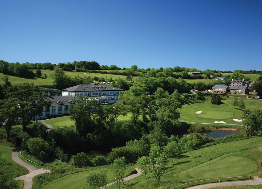 An aerial view of a golf course with a house in the background