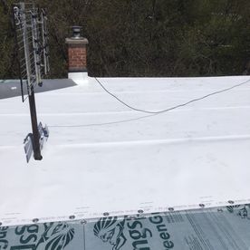 Toit plat blanc avec antenne et cheminée en briques.