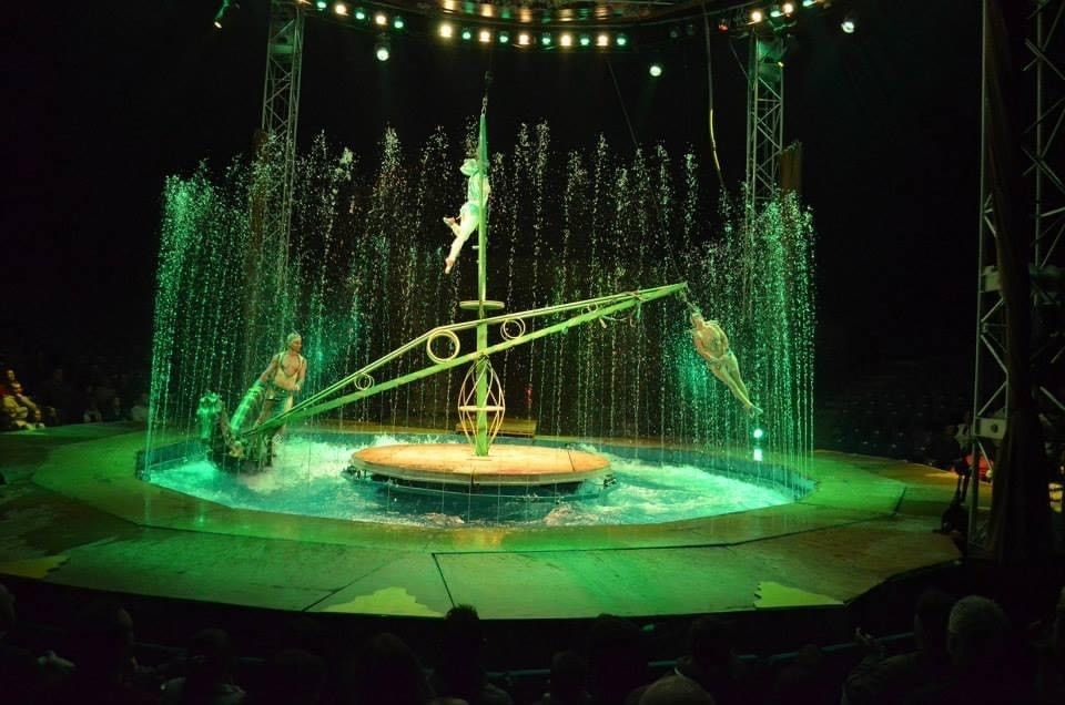 A group of people are performing on a stage in front of a fountain.