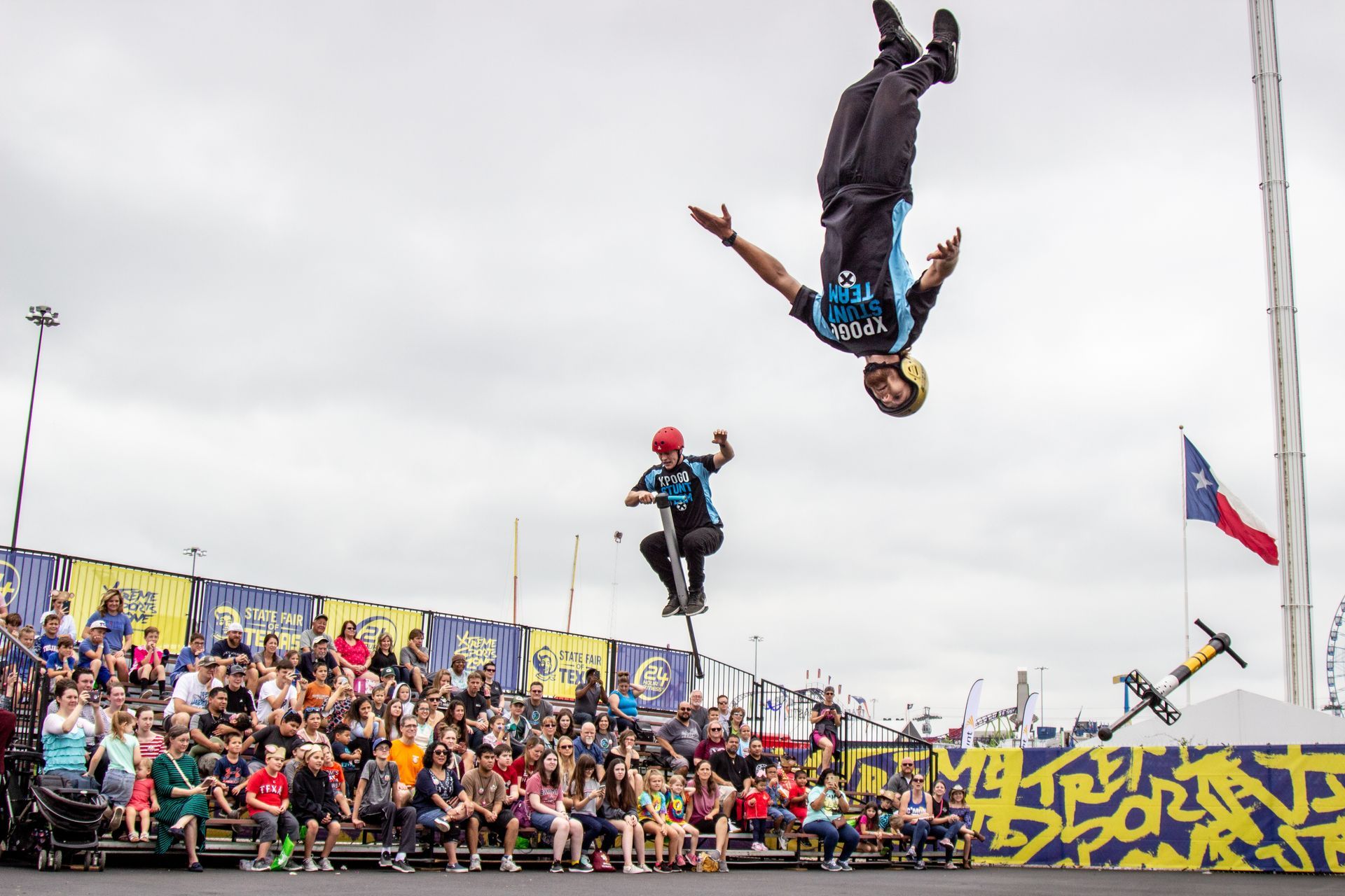 A man is doing a trick in the air while riding a scooter.