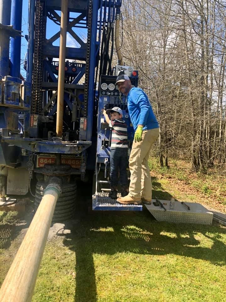 A man and a boy are standing next to a large machine.