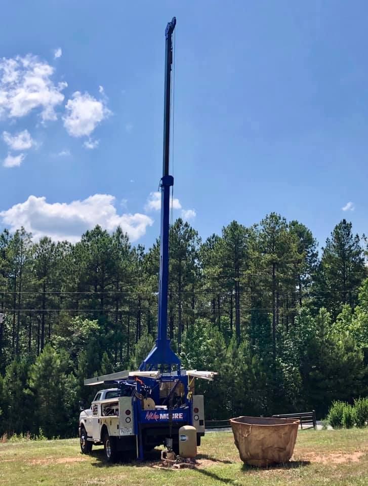 A truck is parked in a grassy field next to a crane.