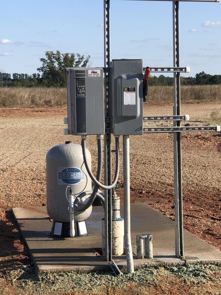 A man is standing on the roof of a house holding a hose.
