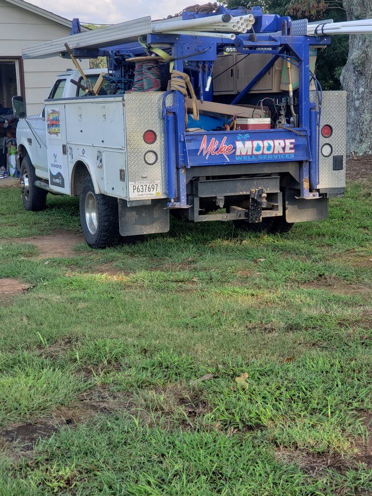 A utility truck is parked in a grassy field in front of a house.