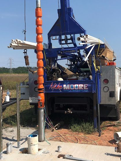 A blue truck with the word moore on the back is parked in a field.