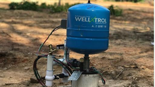 A blue water tank is sitting on top of a well.