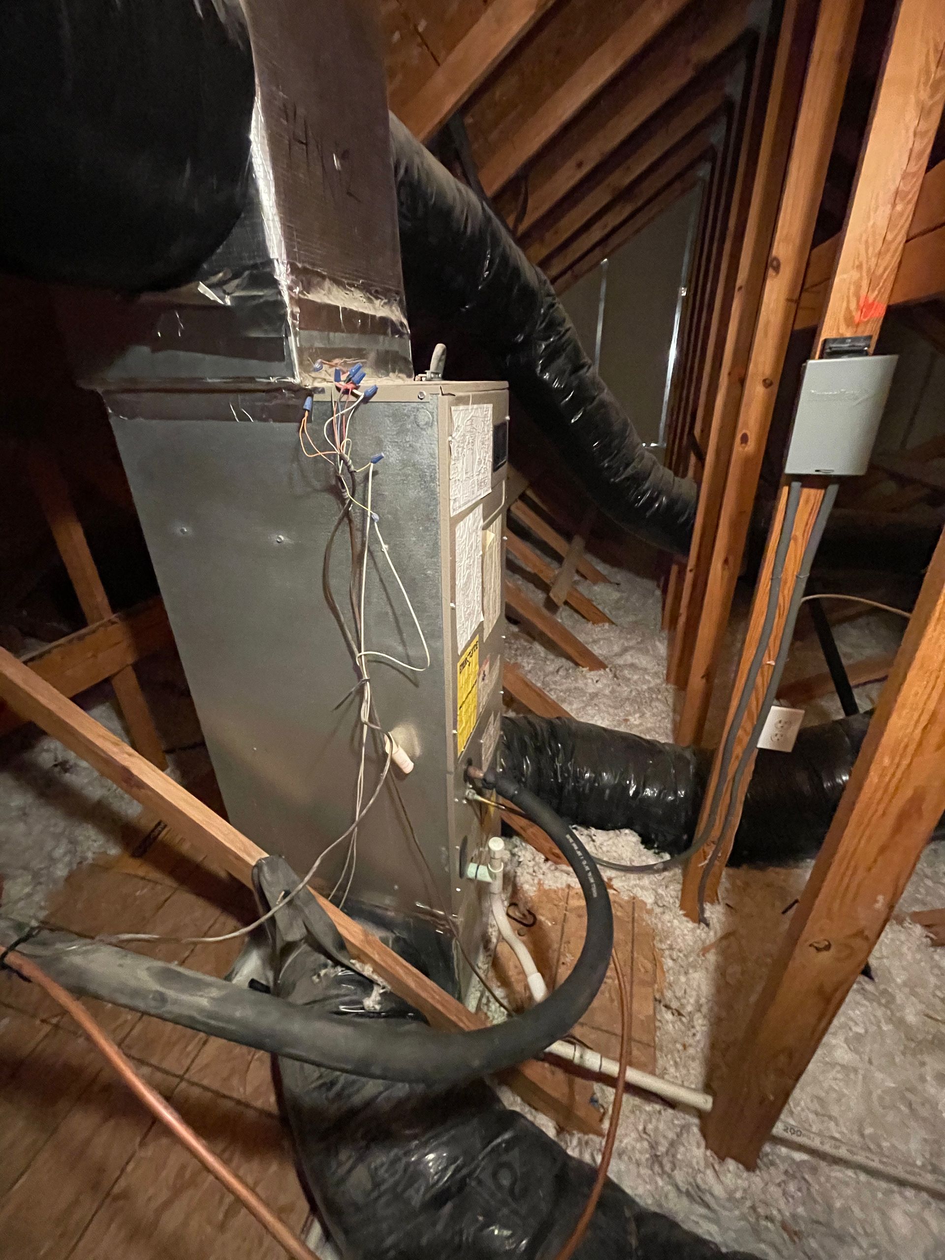 An air conditioner is sitting in the attic of a house.