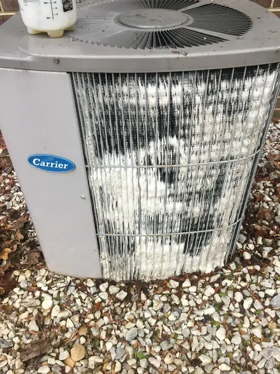 A carrier air conditioner is sitting on a pile of gravel.