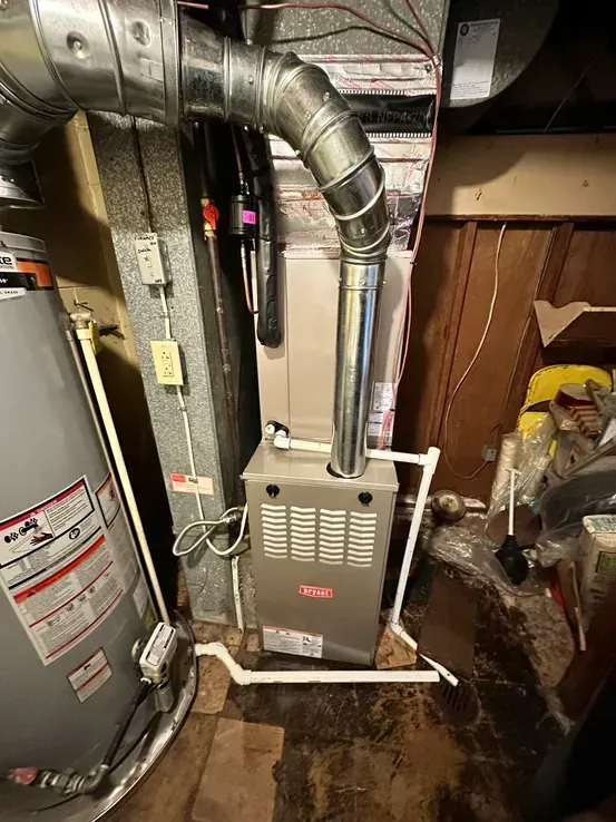 A water heater is sitting next to a furnace in a basement.