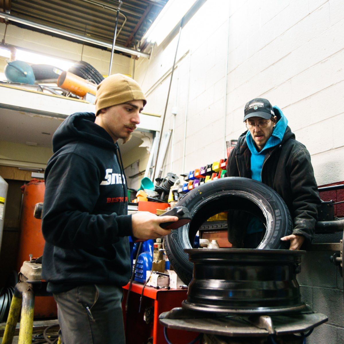 Auto Technicians Installing Tire And Wheel Inside Shop | My Family Car Care Center