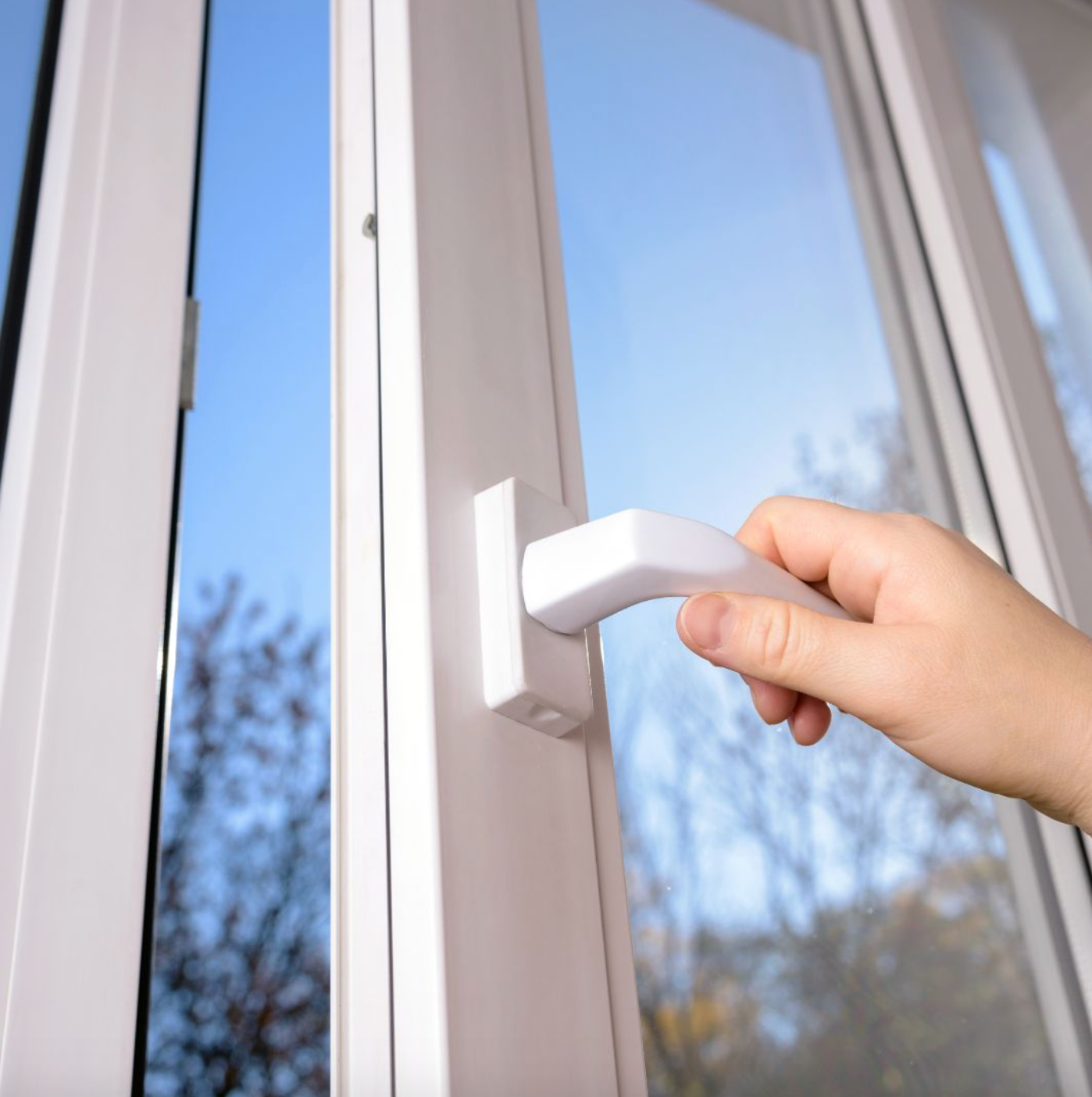 A person is opening a window with a white handle.