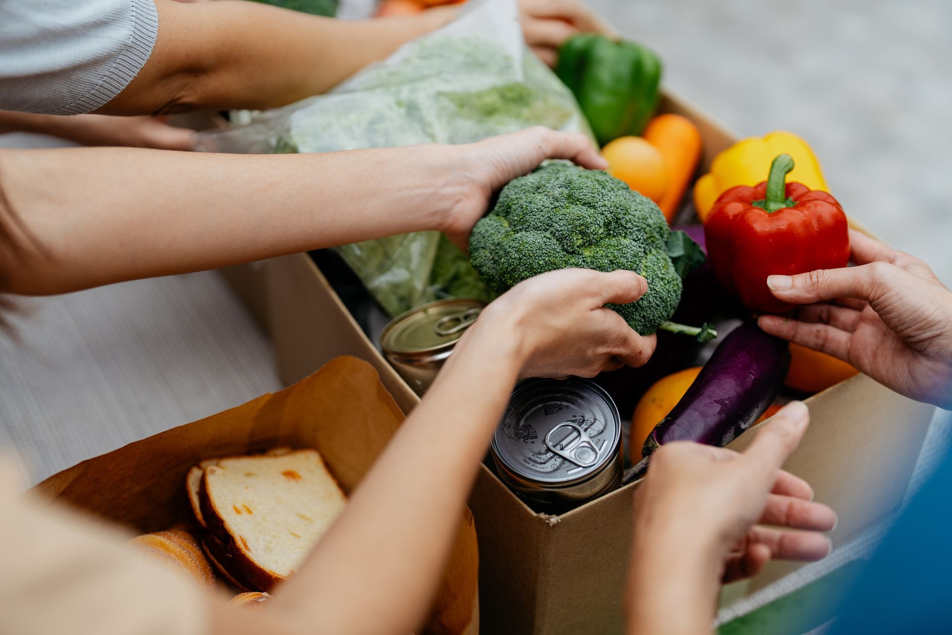 A person is giving a box of vegetables to another person.