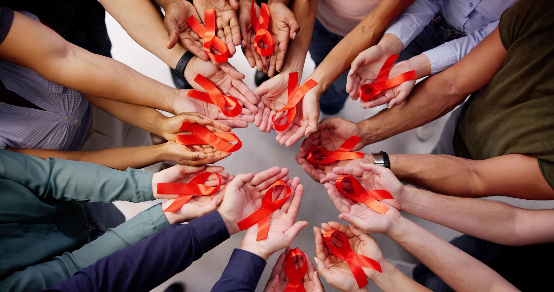 A group of people are holding red ribbons in their hands in a circle.