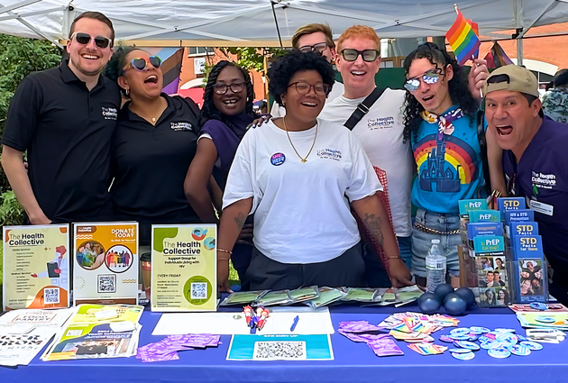 A group of Health Collective staff and volunteers posing at the Health Collective's table at Middletown Pride.