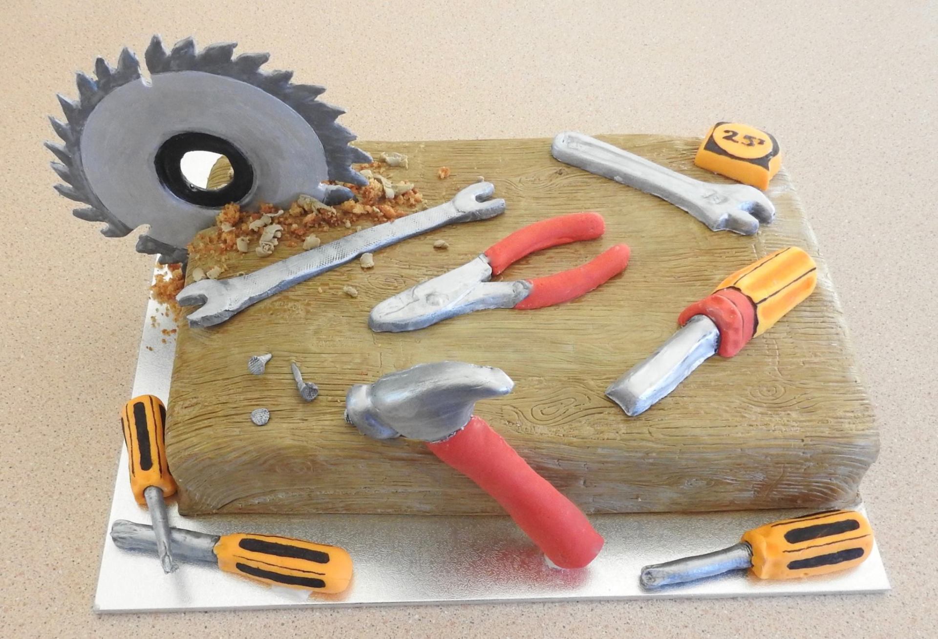 Handyman Birthday Cake woodgrain effect with a saw going through one end and lots of handyman tools.